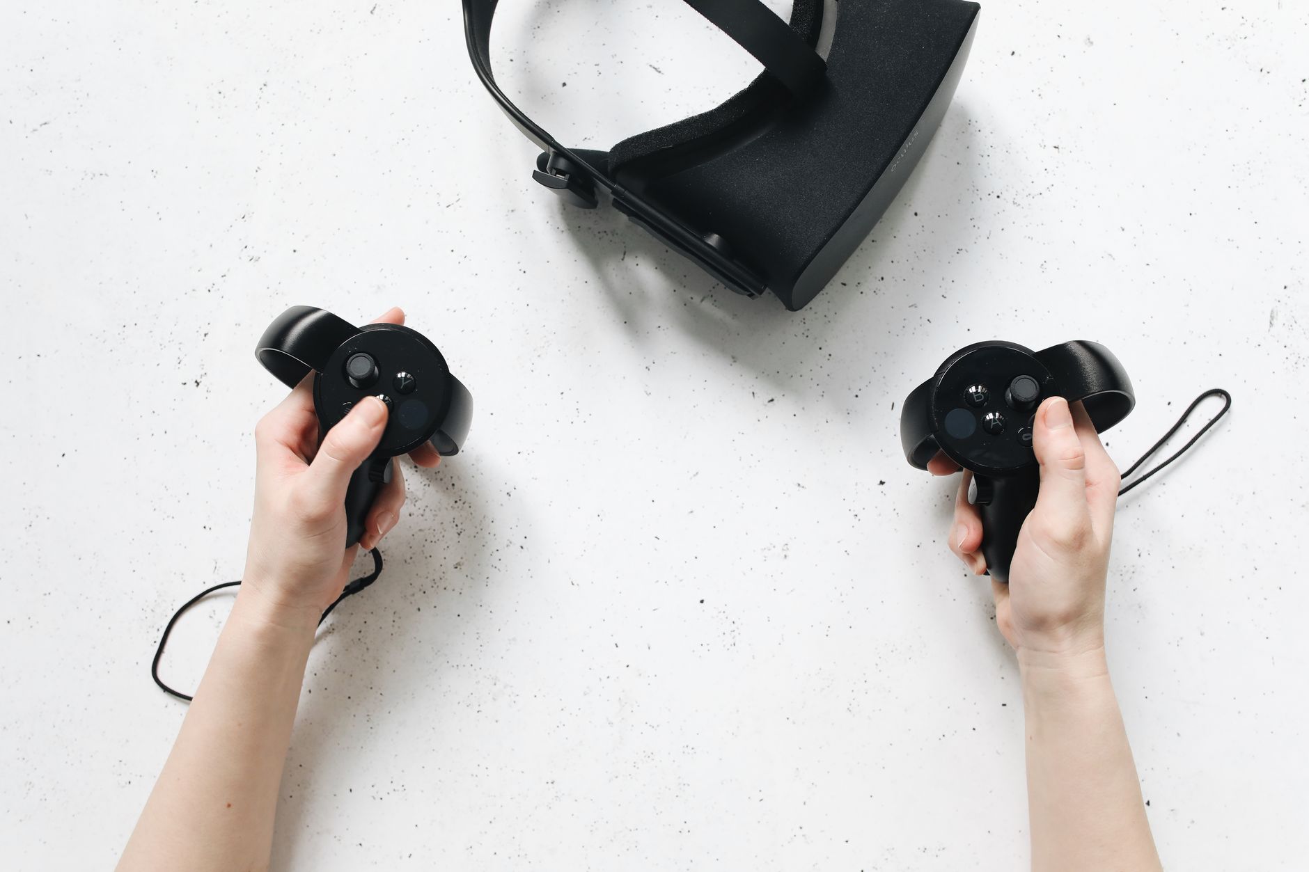 Dłonie trzymające kontrolery VR obok gogli, kadr poglądowy