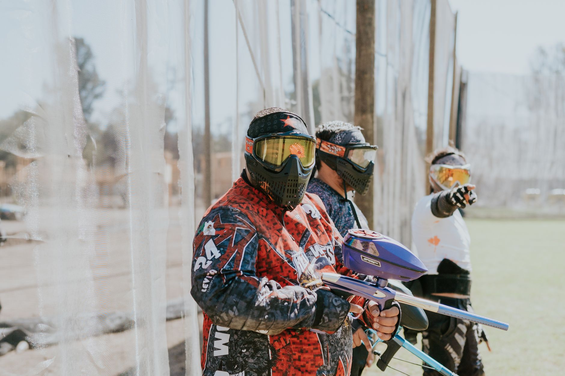 Trzech graczy paintballa w maskach i kolorowych strojach