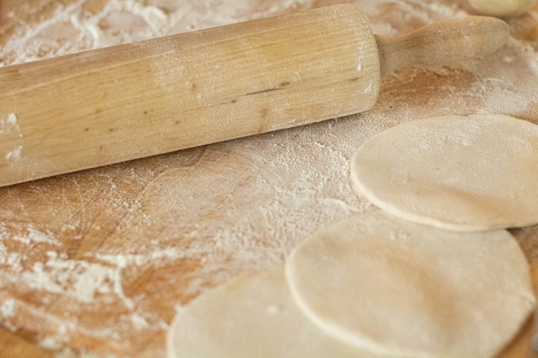 Rozwałkowane ciasto i wałek na desce oprószonej mąką