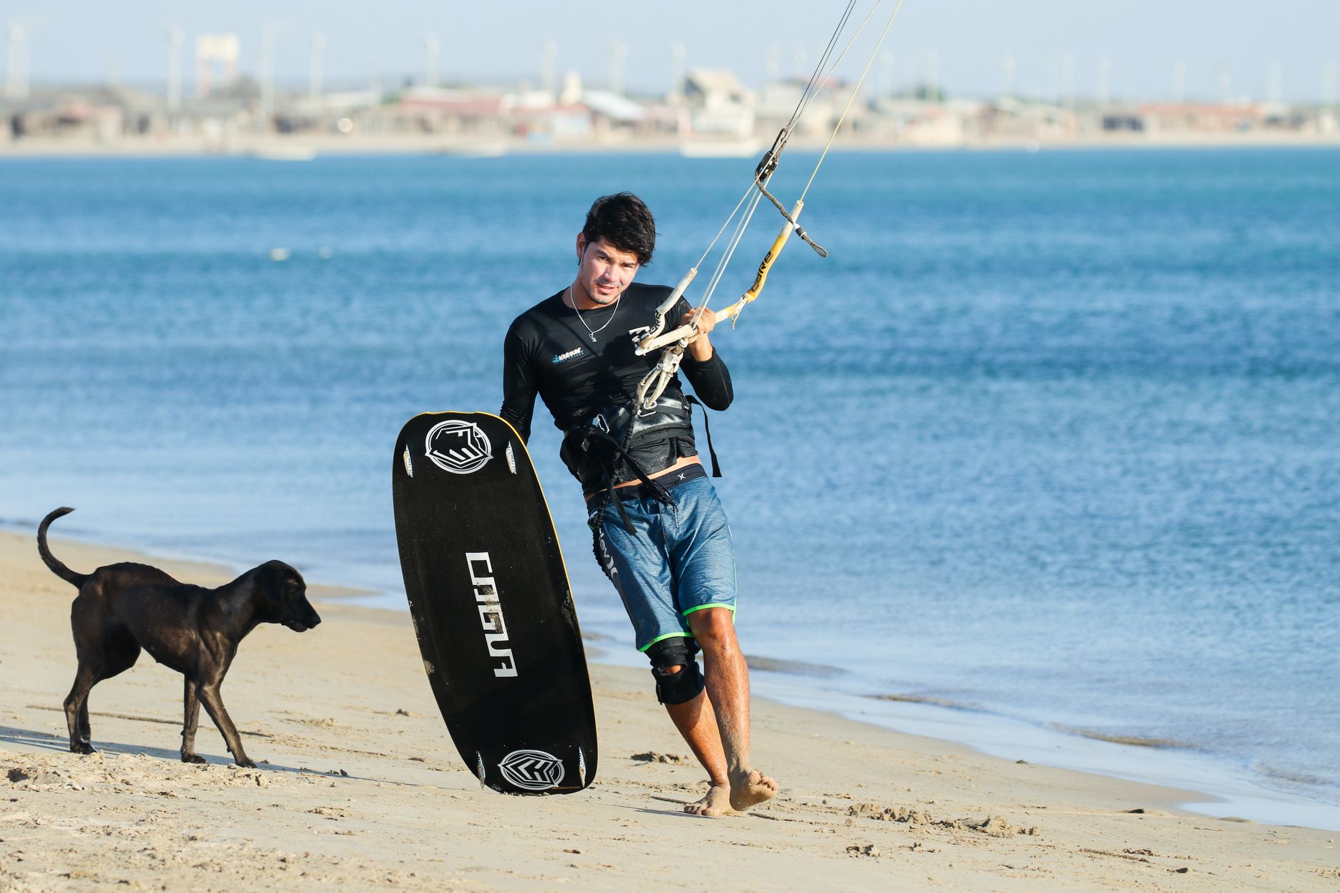 Kitesurfer z deską i psem na plaży