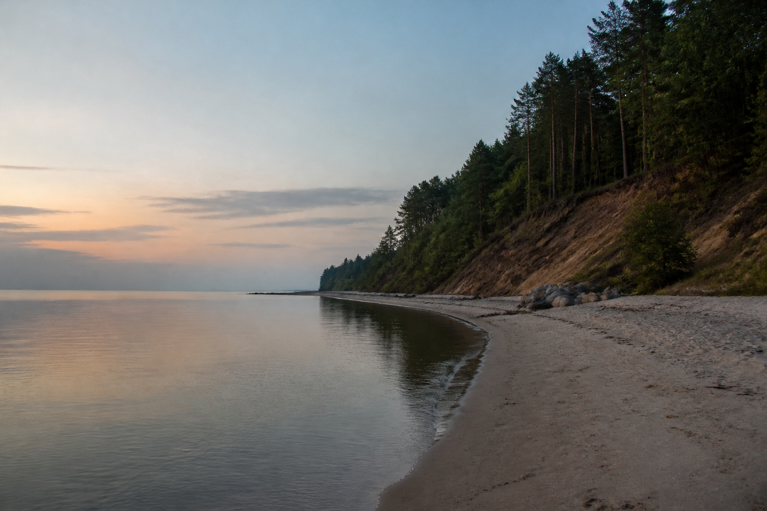 Spokojna bałtycka plaża pod zalesionym klifem o zmierzchu